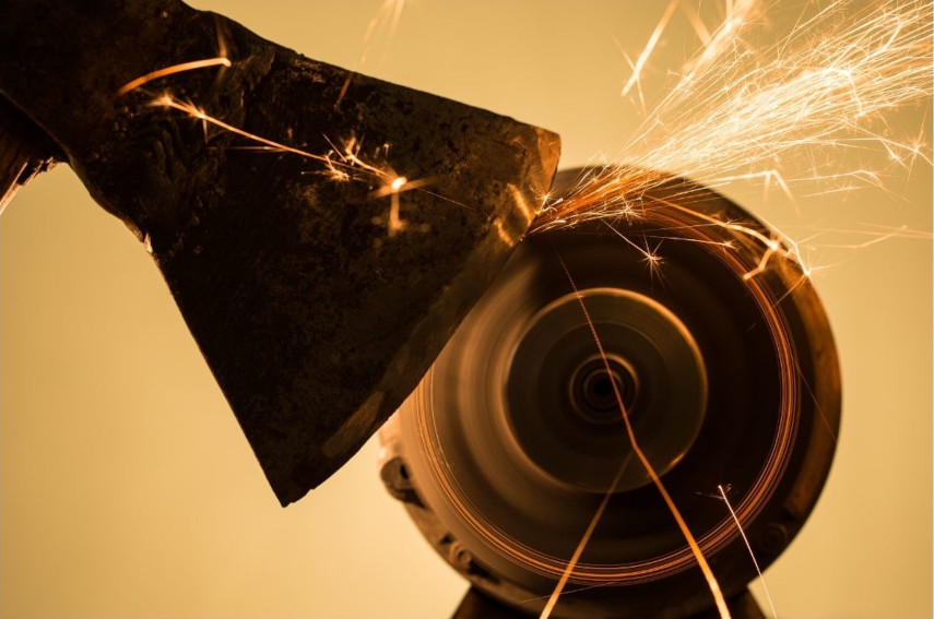 Sliper en øks, gnister fra slipemaskinen